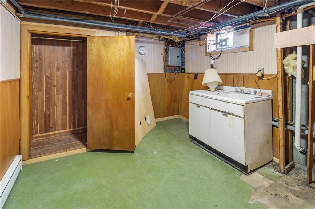 Basement with wood paneling, washer, and open door to a wood-lined room, green floor.