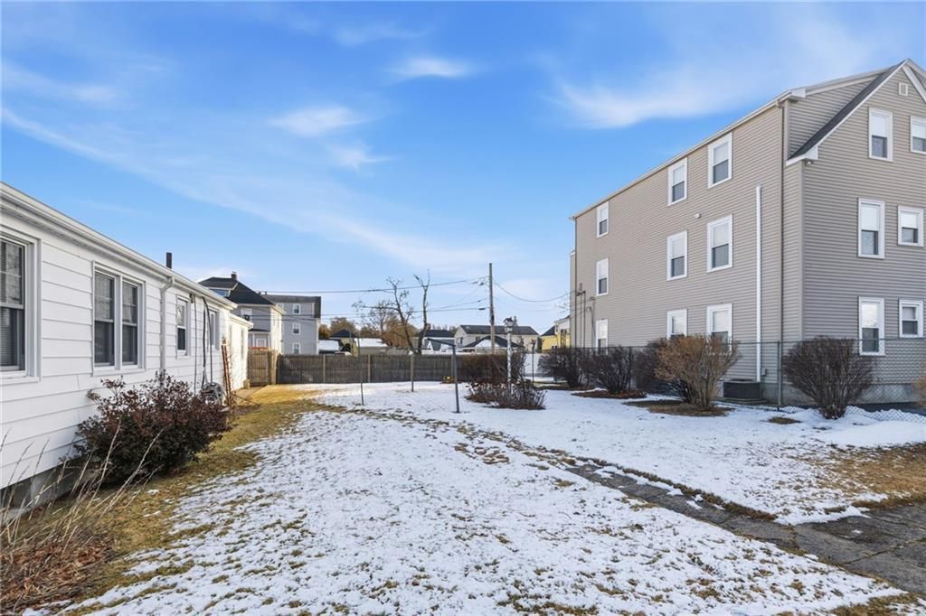 A snowy backyard between two multi-unit apartment buildings under a blue sky.