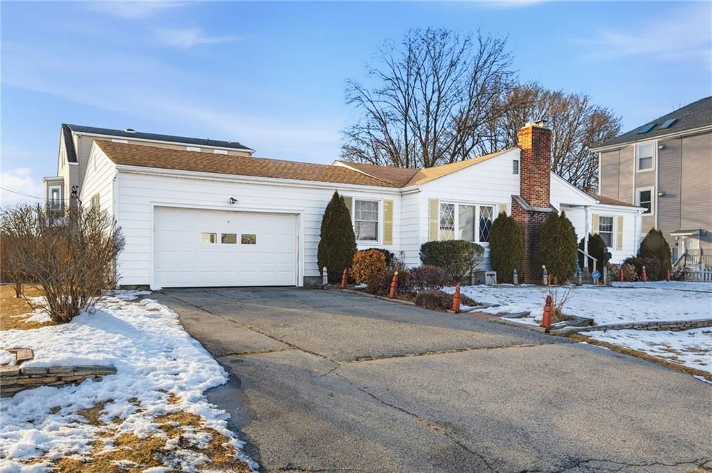 White suburban house with a driveway and garage, winter setting, snow present.
