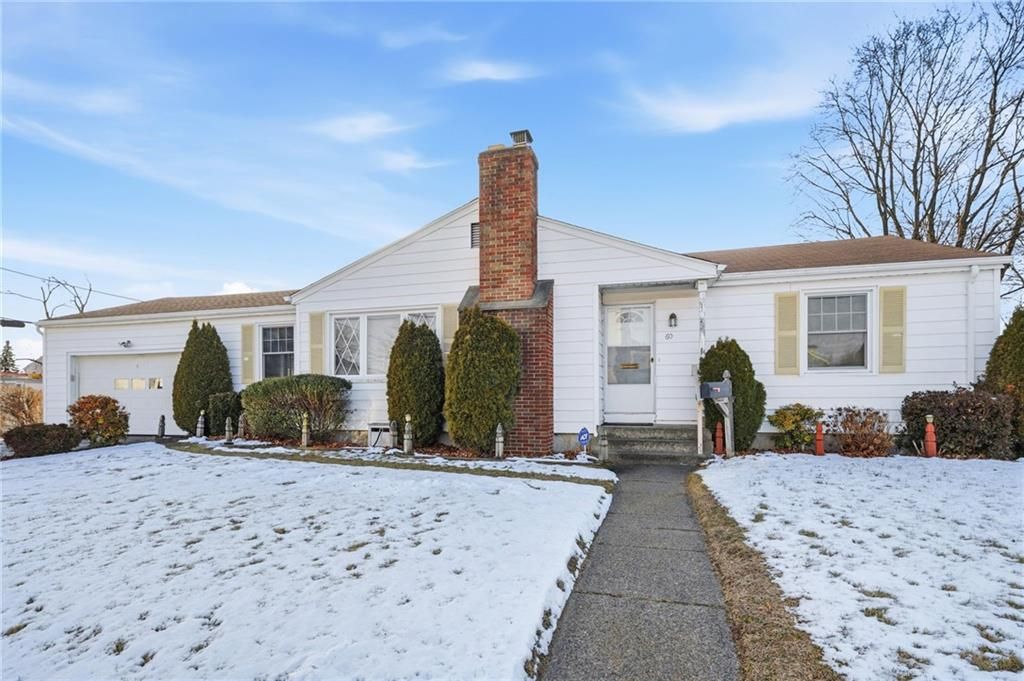 White ranch-style house with brick chimney in a snowy setting, pathway leading to front door.