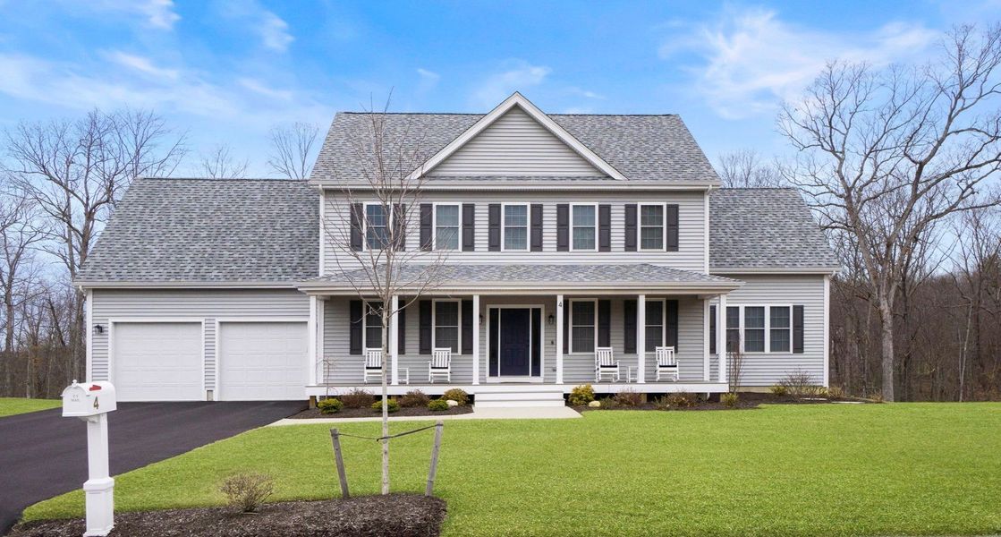 Two-story gray house with a porch, lawn, and driveway.