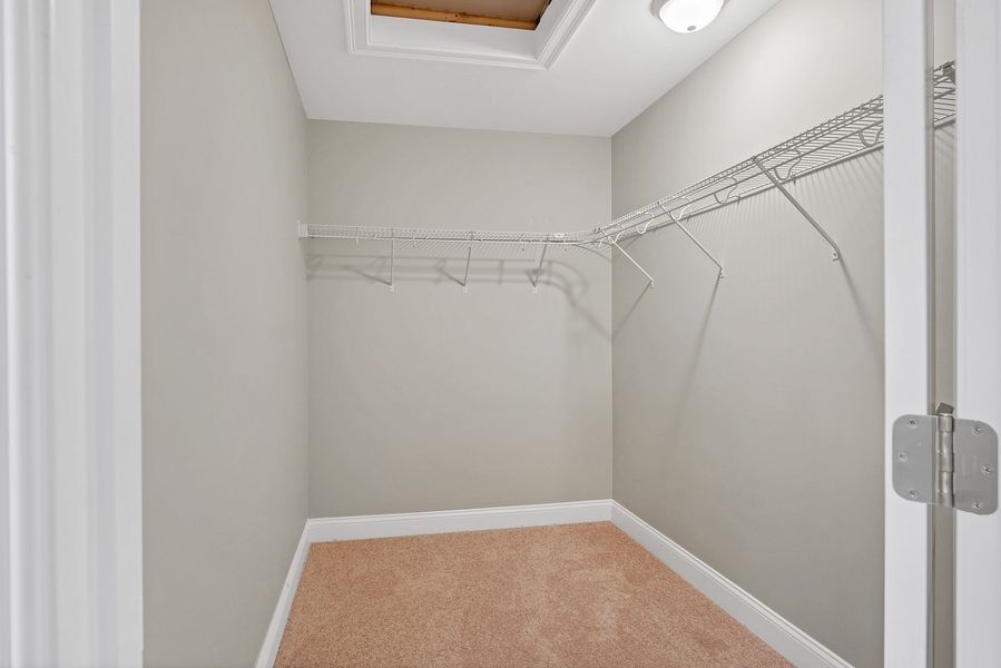 Empty walk-in closet with wire shelving, light-colored walls and carpet, and an open doorway.