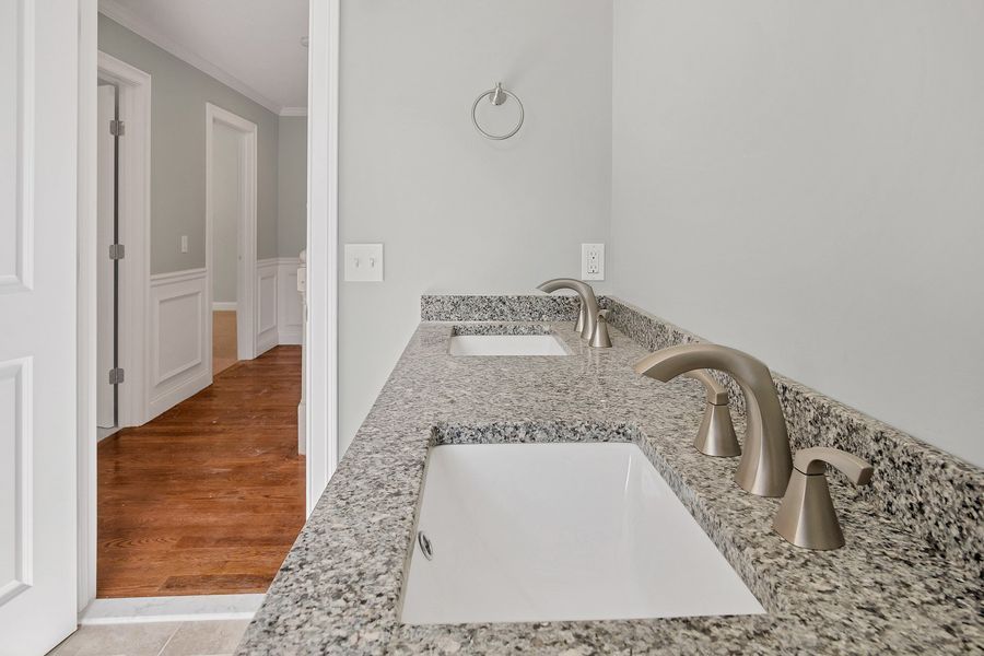Bathroom with double vanity, granite countertop, two sinks, and brushed nickel faucets. Gray walls and doorway.