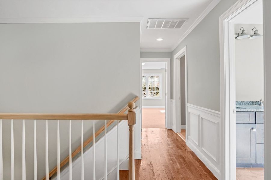 Hallway with wooden floor, white trim, grey walls, and a staircase.