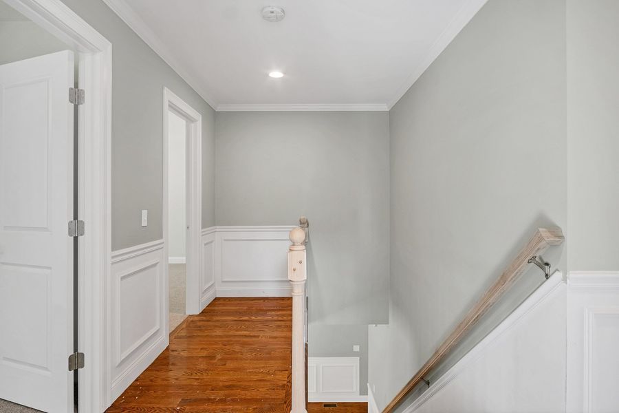 Hallway with grey walls, white trim, and hardwood floors. Staircase on the right.