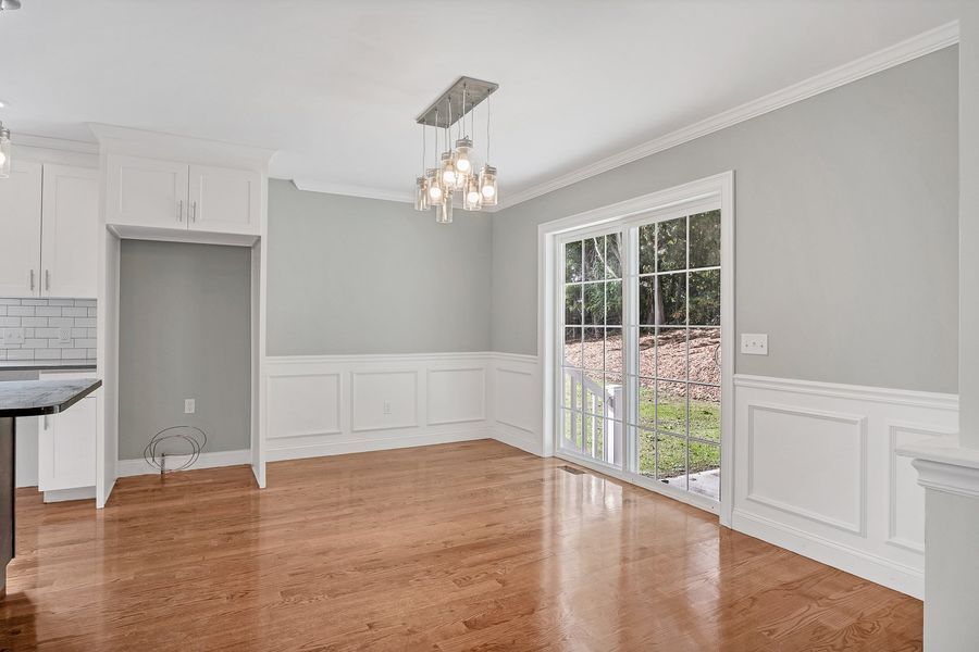 Empty dining room with wood floors, light gray walls, and glass sliding door.