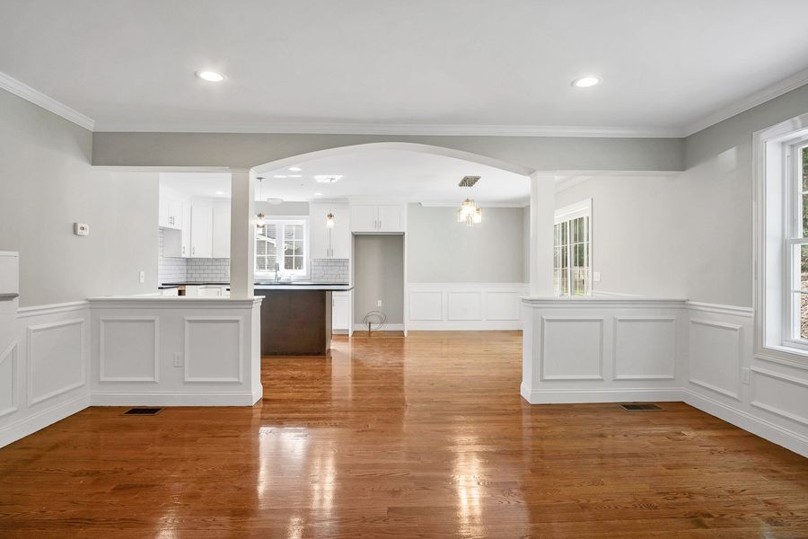 Spacious open-concept interior with hardwood floors, white trim, and a view into the kitchen.