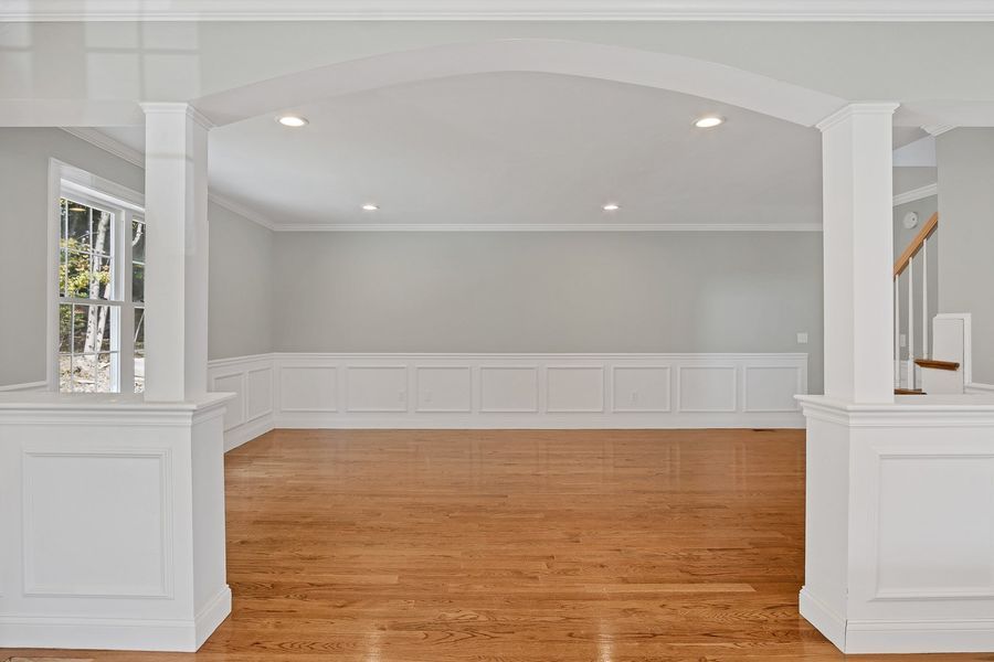 Empty room with hardwood floors, white trim, and built-in storage.