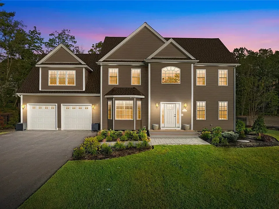 Two-story gray house with a driveway and green lawn. Has a garage and a porch.