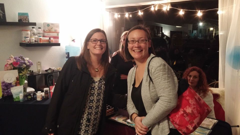 Two women are standing next to each other in a room and smiling.