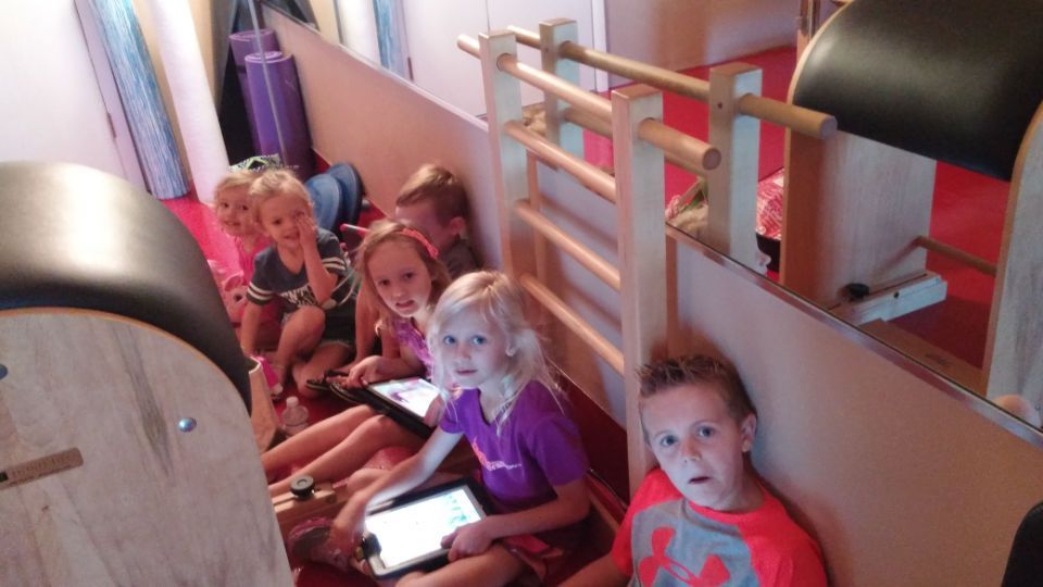 A group of children are sitting next to each other using tablets.