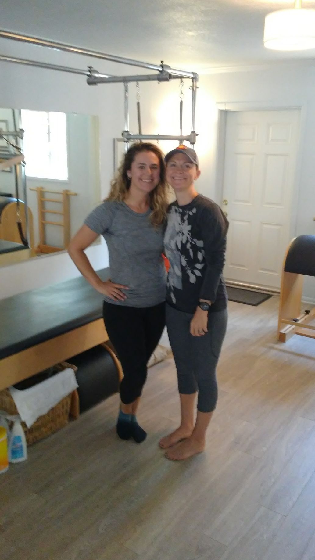 Two women are posing for a picture in a pilates studio.