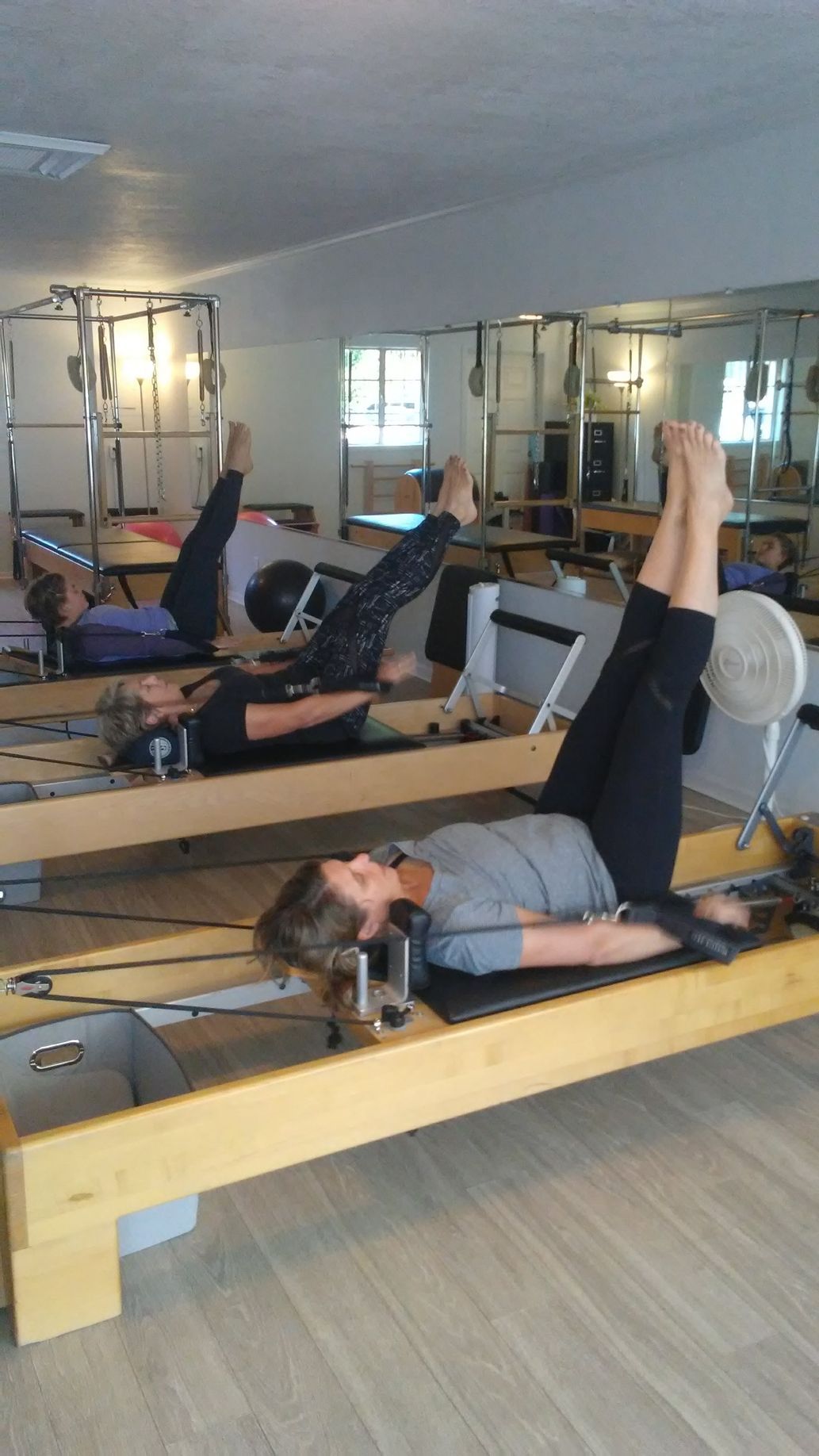 A group of people are doing pilates exercises in a gym.