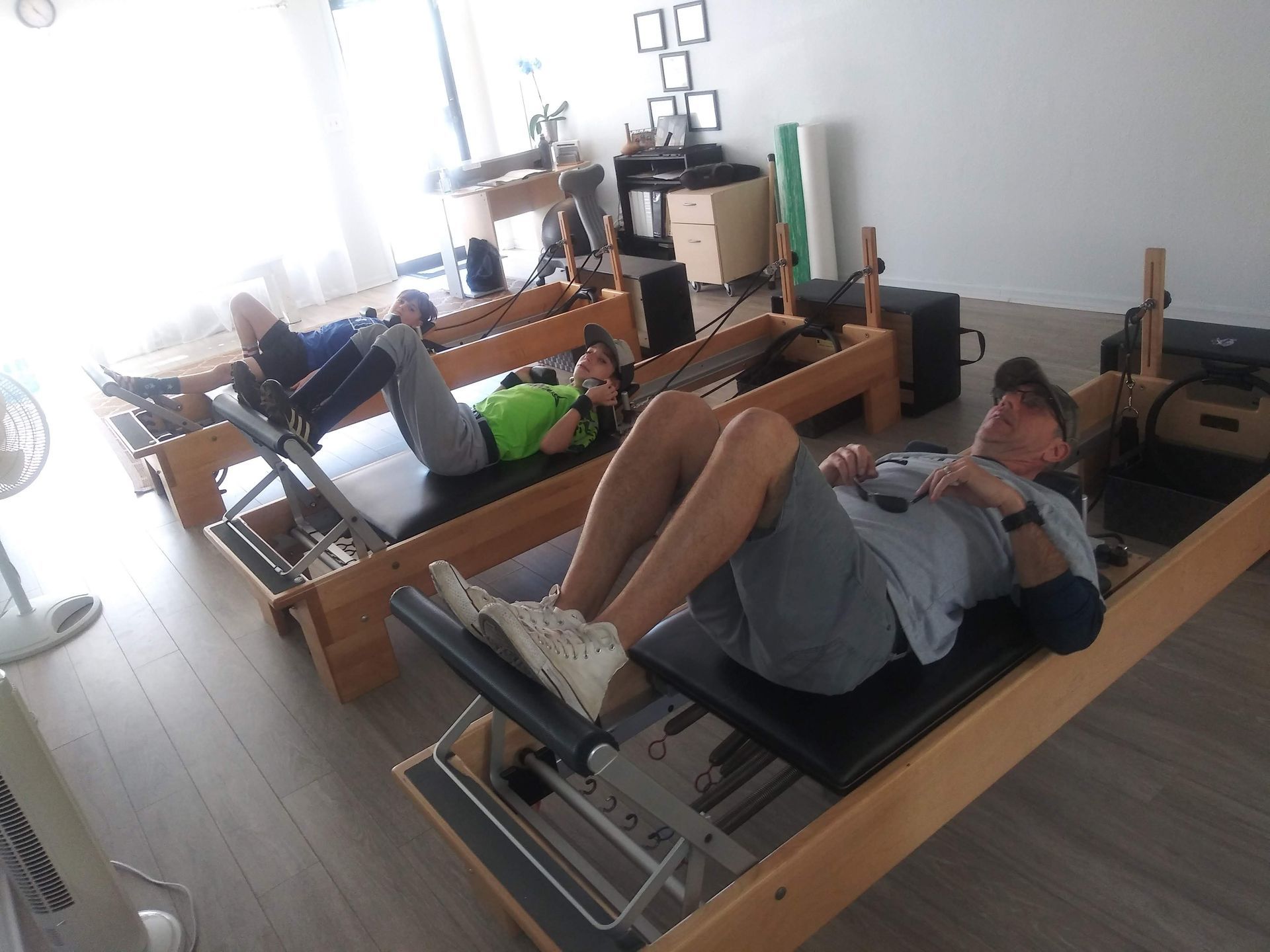 A group of people are laying on pilates machines in a gym.