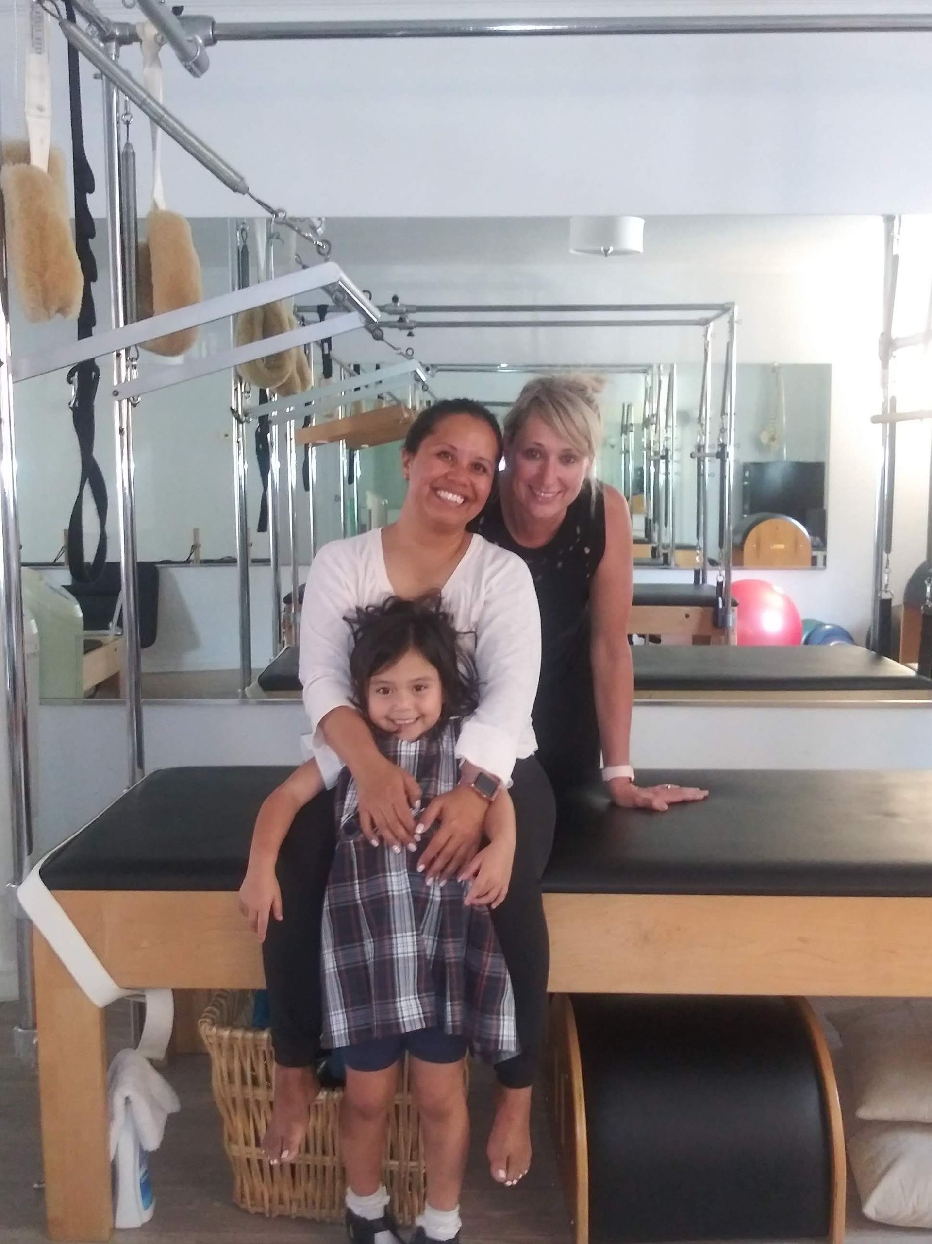 Two women and a child pose for a picture in a gym