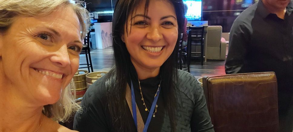 Two women are smiling for a picture in a restaurant.