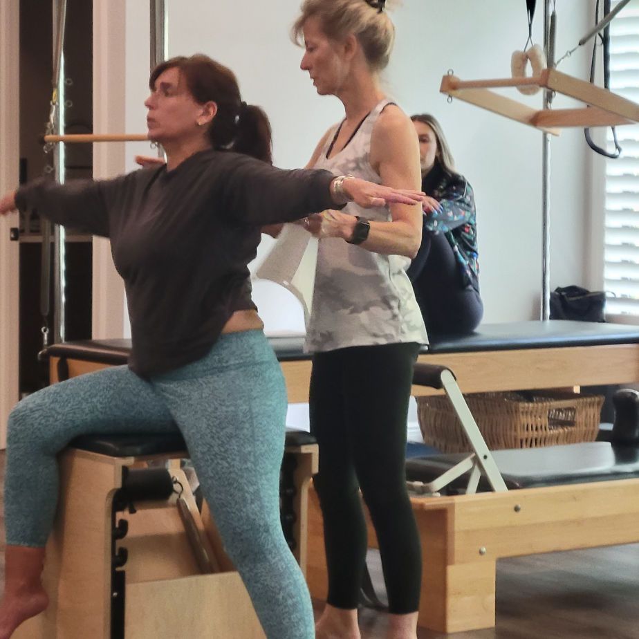 Two women are doing exercises on a pilates machine