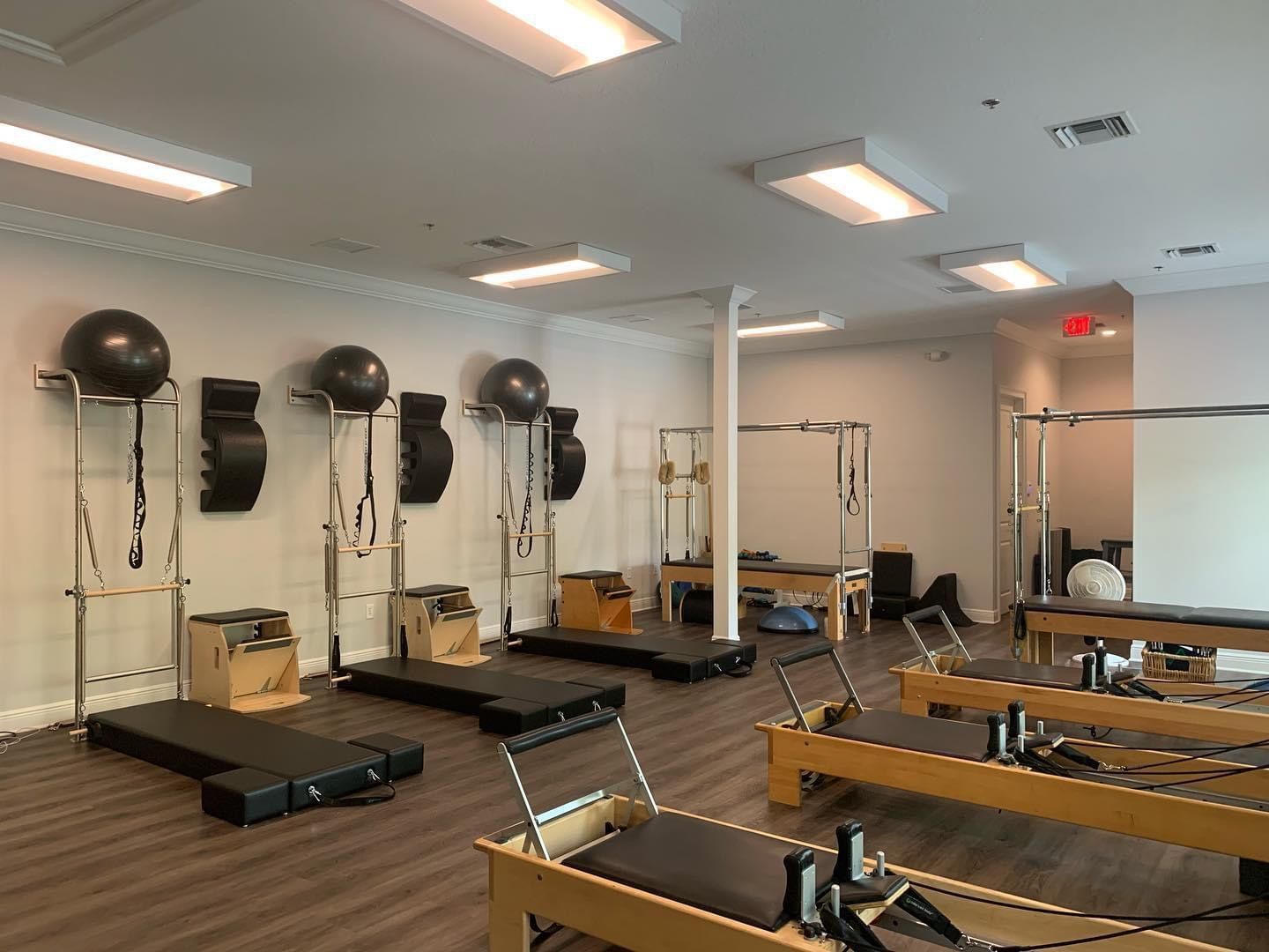 A large room filled with lots of pilates equipment.
