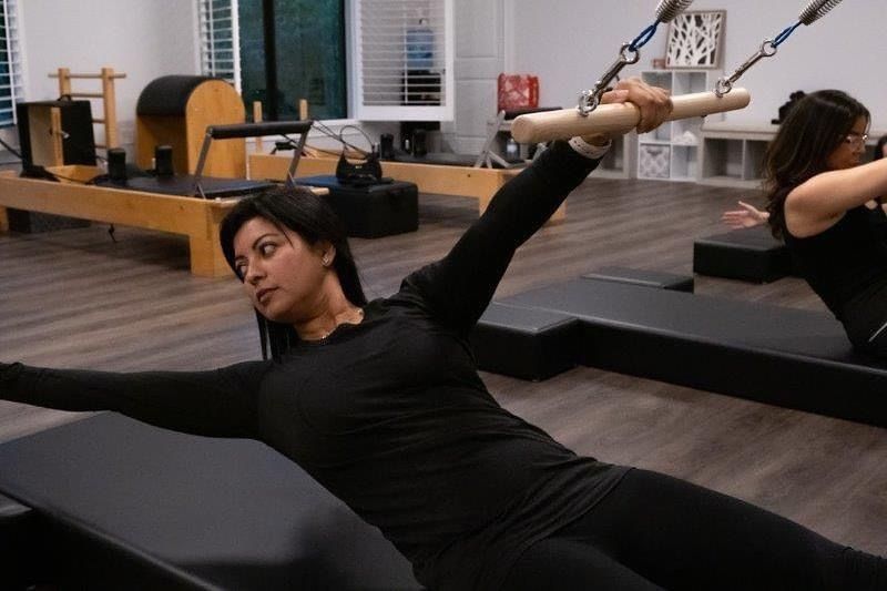 A woman is doing pilates on a pilates machine in a gym.