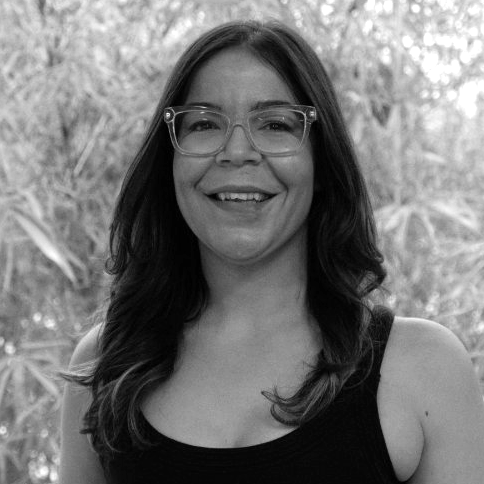Marysol wearing glasses and a black tank top is smiling in a black and white photo .