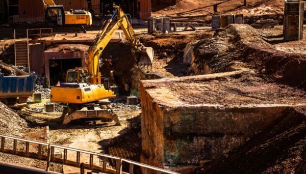 A yellow excavator is digging a hole in a construction site.