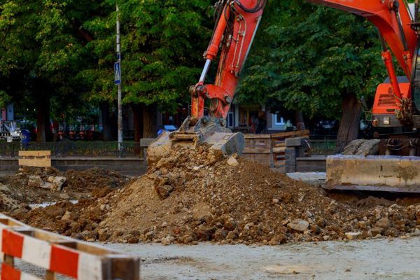 A large orange excavator is working on a construction site.
