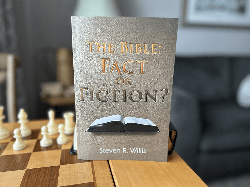 A book titled the bible : fact or fiction is sitting on a chess board.