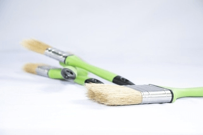This is a picture of four paint brushes. The paint brushes have a green handle.