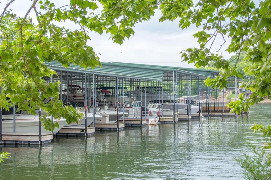 A row of boats are docked at a marina on a lake.