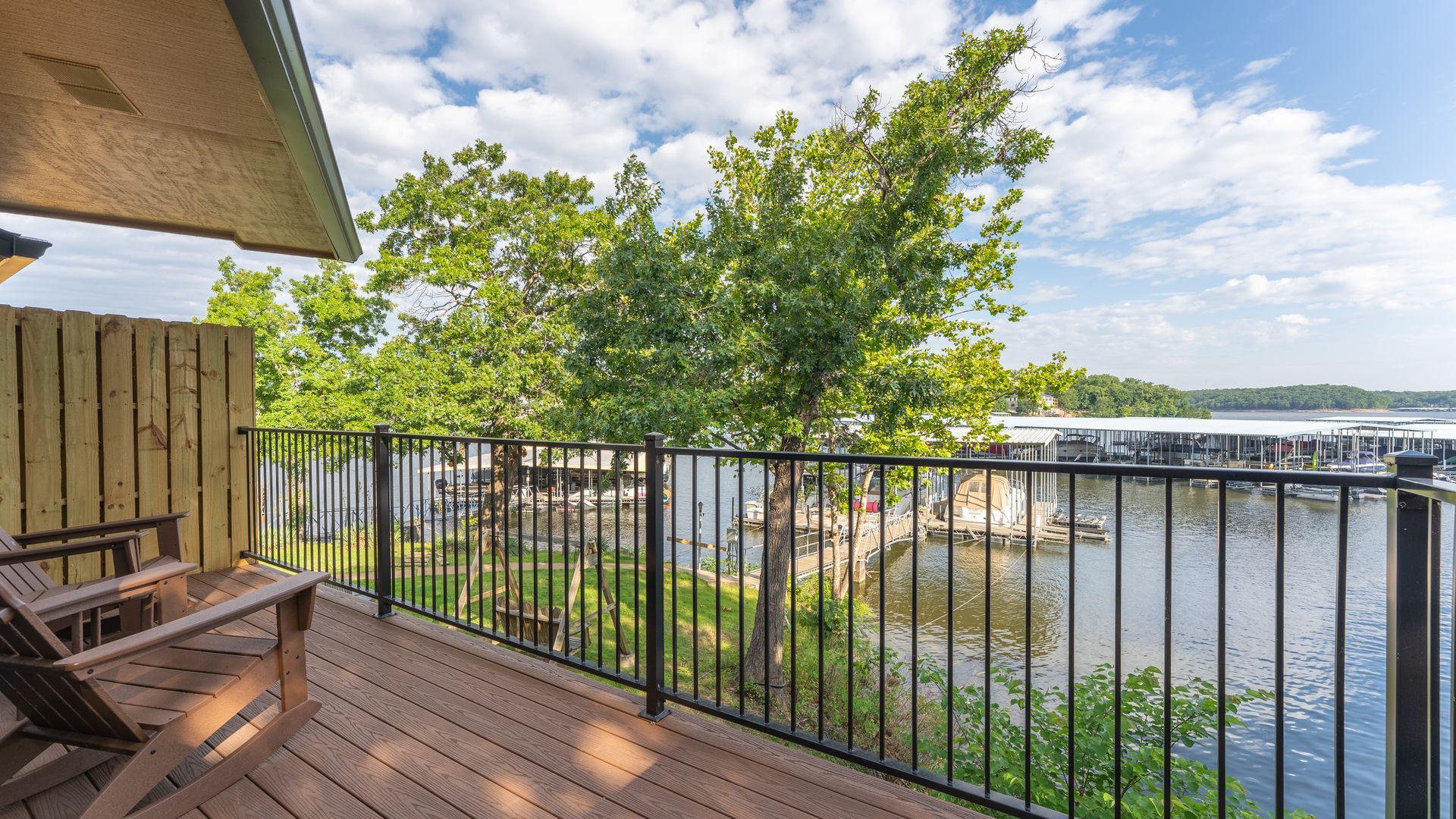 There is a balcony with a view of the water and trees.