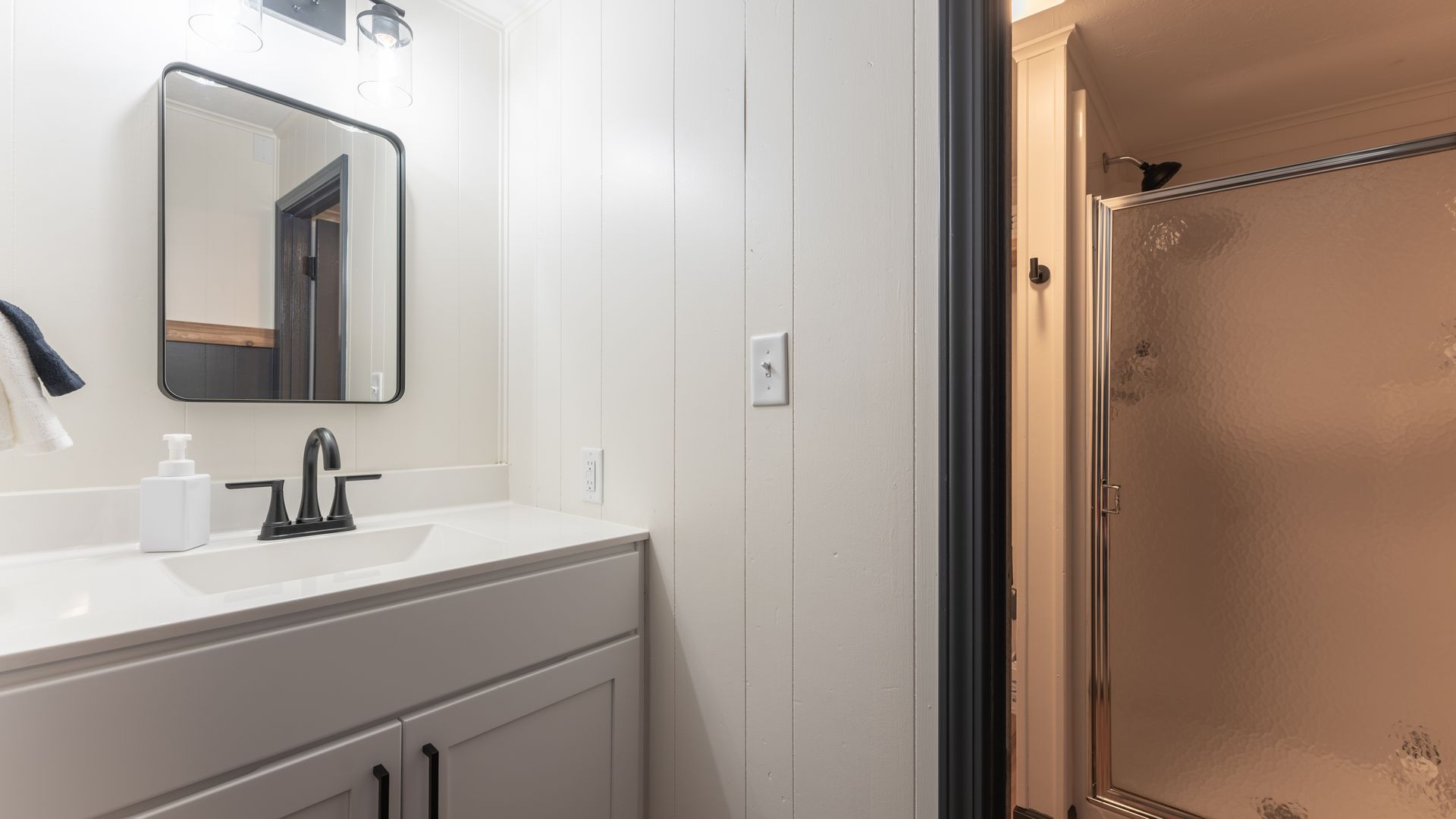 A bathroom with a sink , mirror and shower.