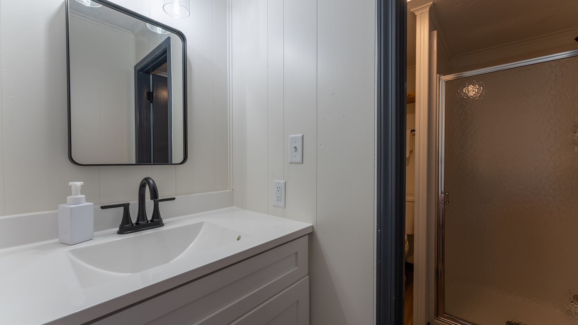 A bathroom with a sink , mirror and shower.