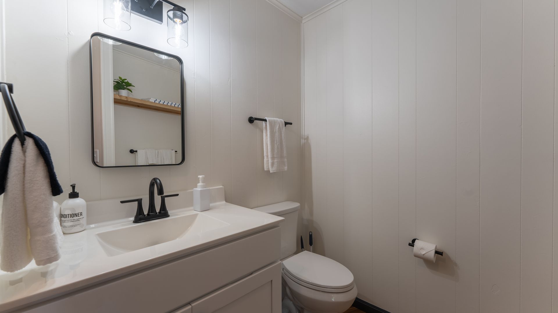 A bathroom with a sink , toilet and mirror.