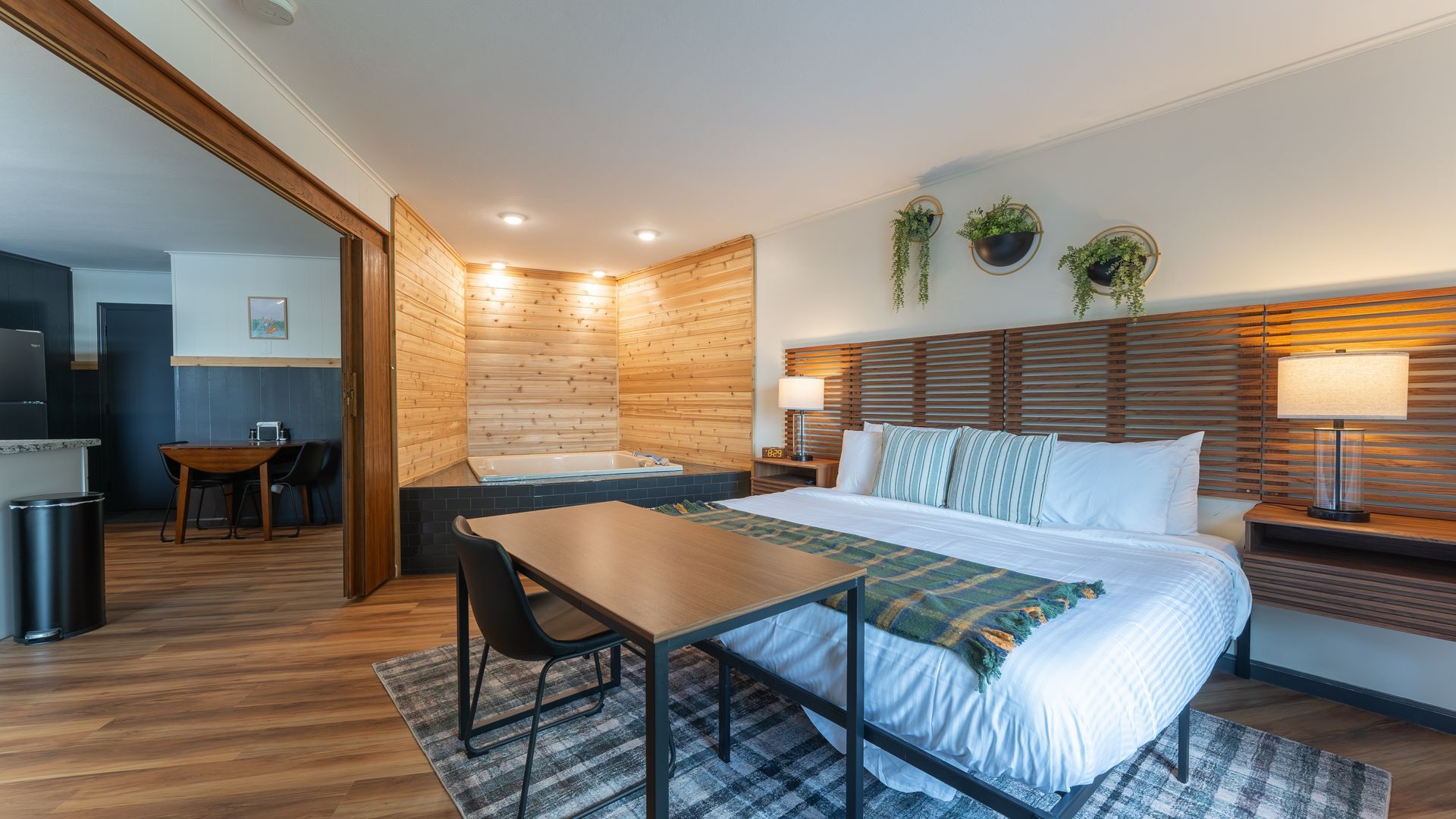 A hotel room with a king size bed , table and chairs.