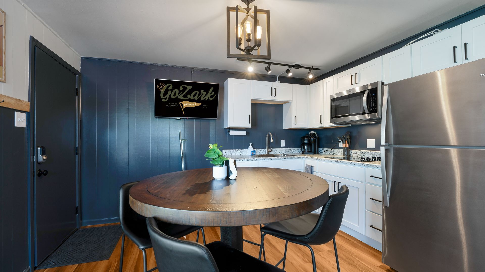 A kitchen with a round table and chairs and a stainless steel refrigerator.