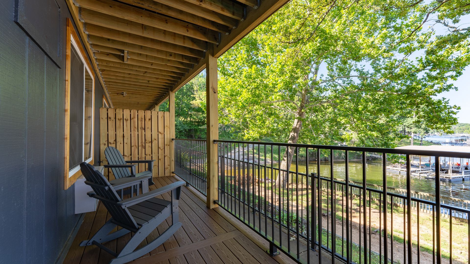 A balcony with chairs and a railing overlooking a lake.