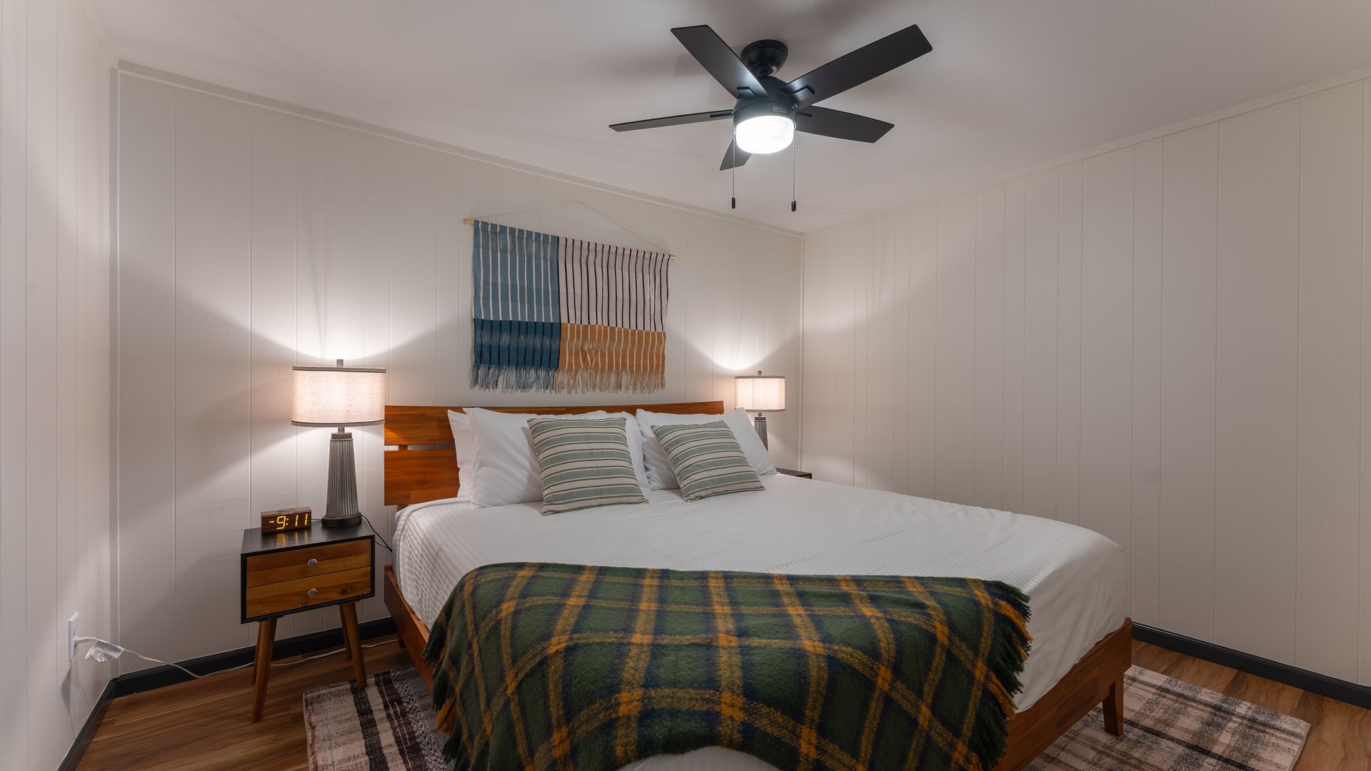 A bedroom with a king size bed and a ceiling fan.