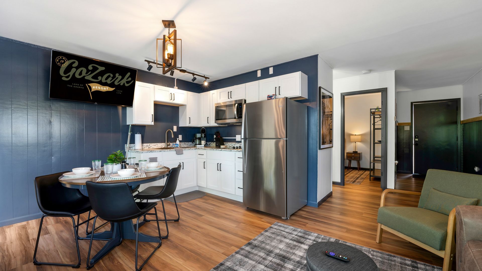 A living room with a dining table , chairs , and a refrigerator.