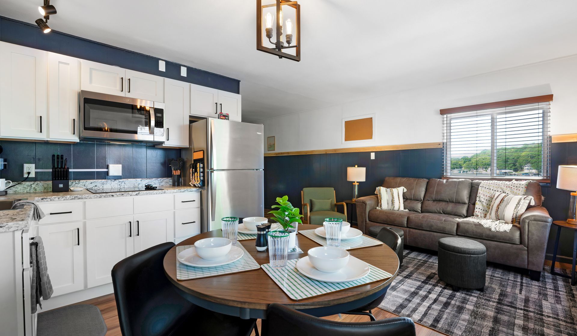 A living room with a couch , table , chairs and a kitchen.