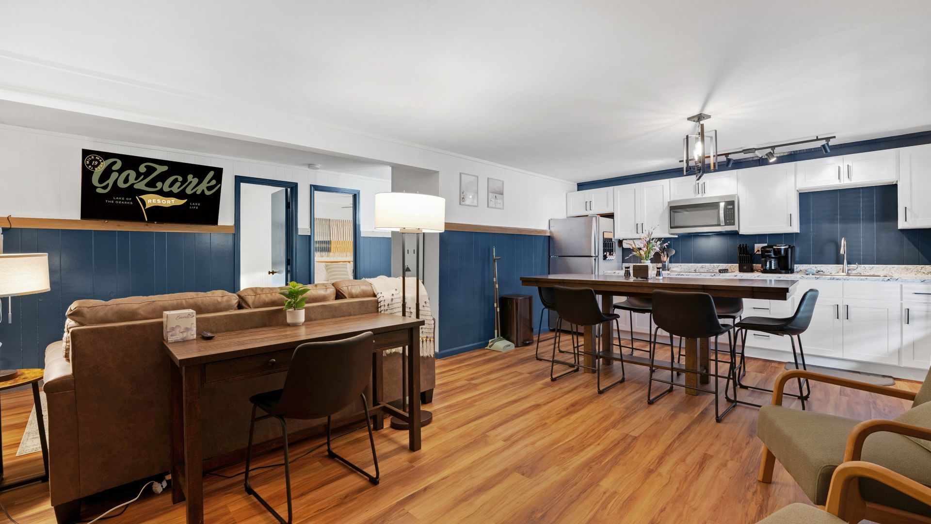 A living room with a couch , table , chairs and a kitchen.