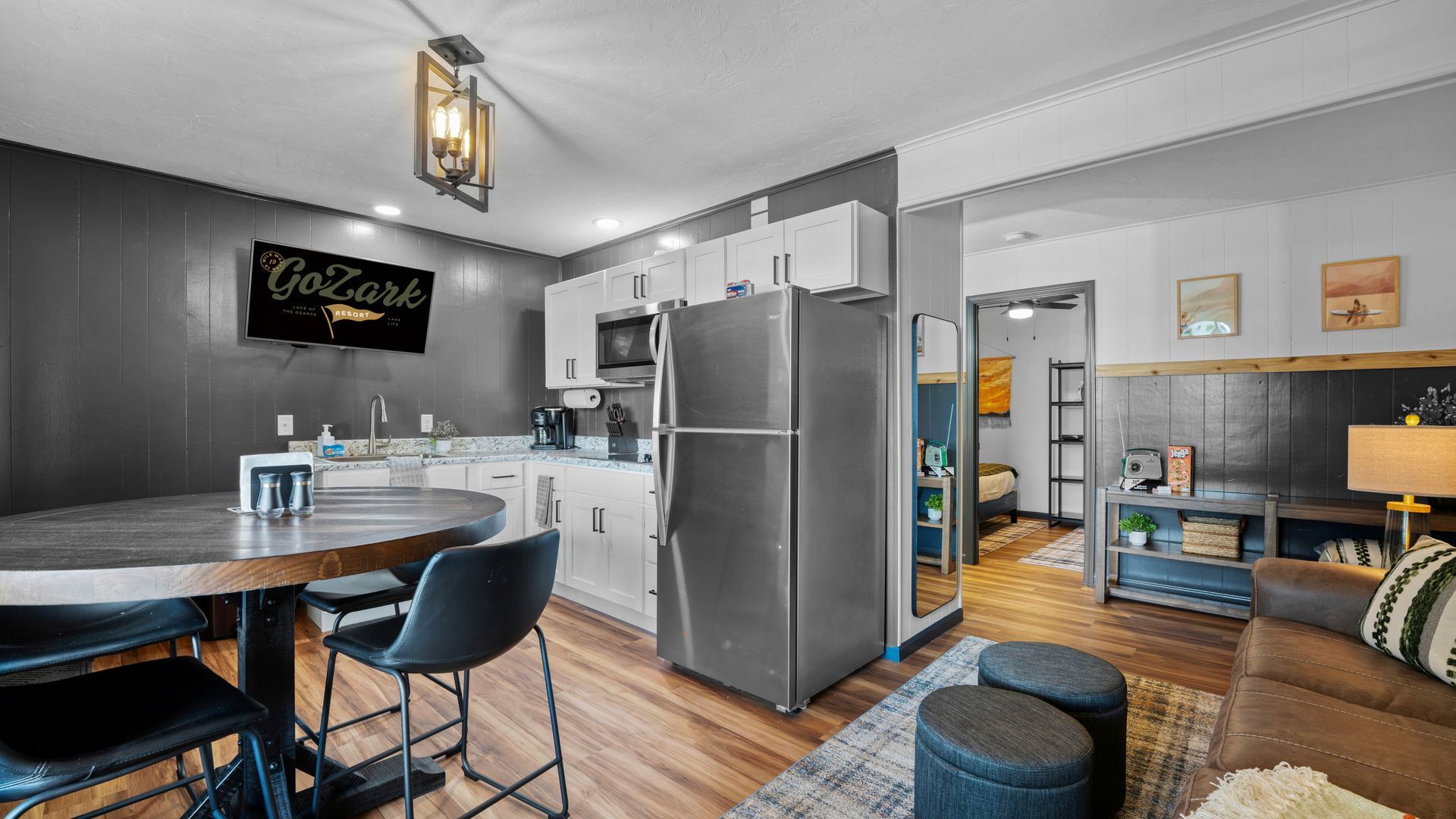 A living room with a table , chairs , and a refrigerator.