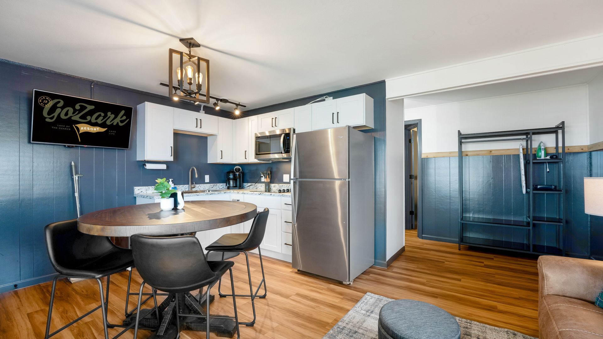 A living room with a table and chairs , a kitchen , and a bunk bed.