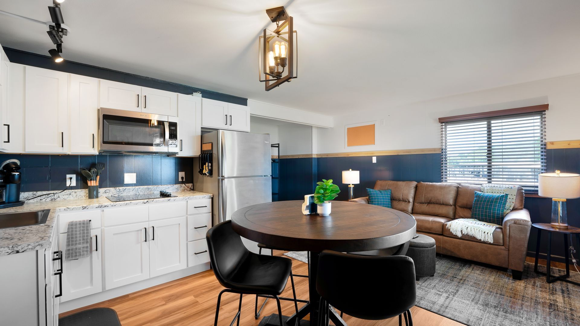 A living room with a couch , table , chairs and a kitchen.