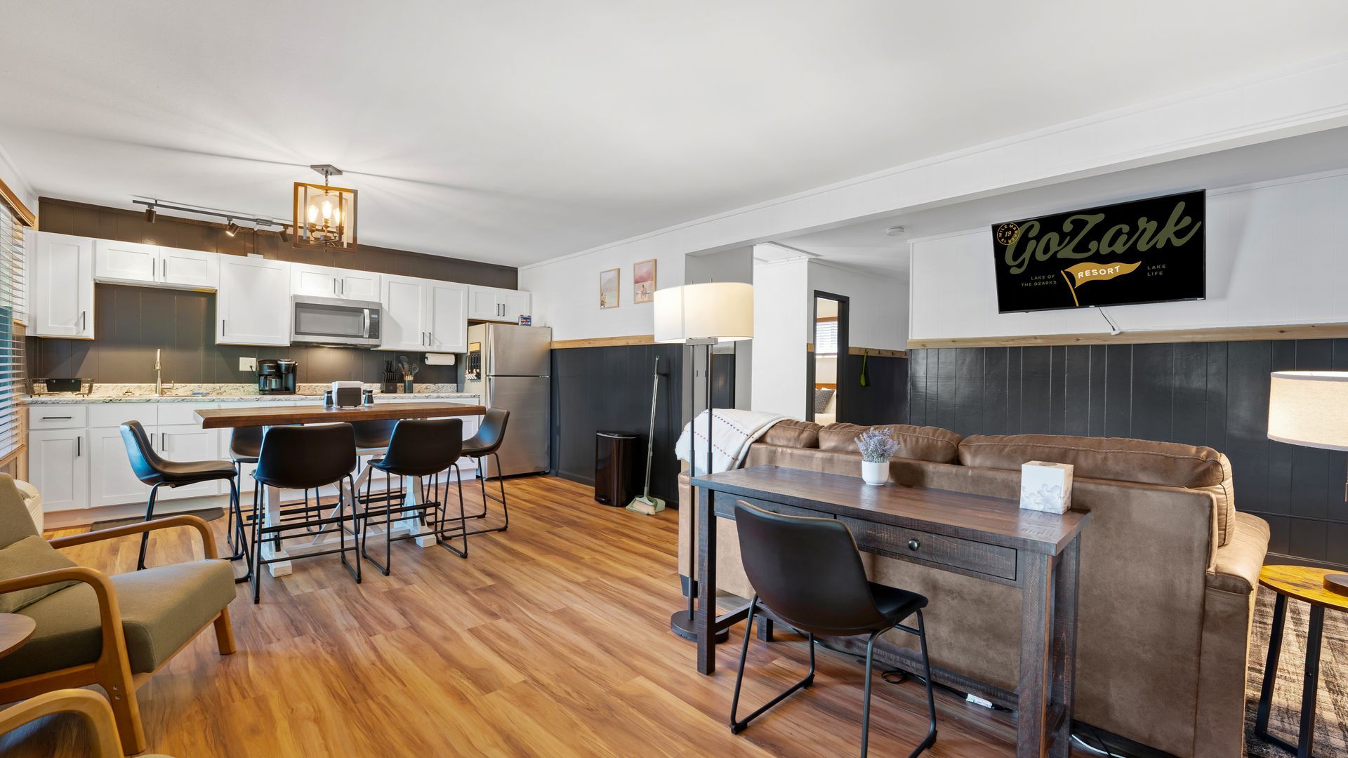 A living room with a couch , table , chairs and a kitchen.