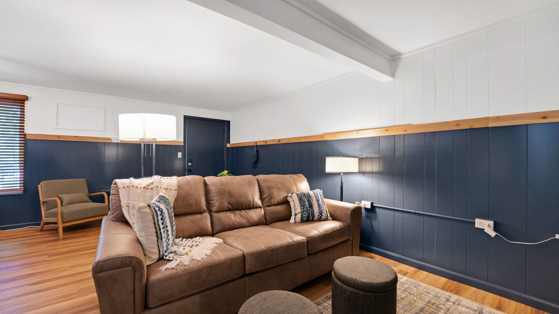 A living room with a couch , chair , lamp and rug.