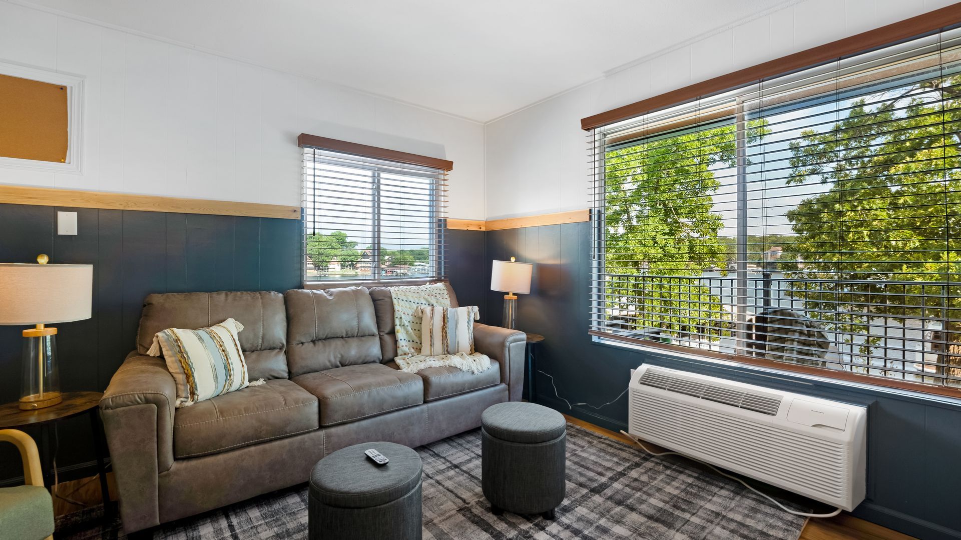 A living room with a couch , chair , ottoman and a window.