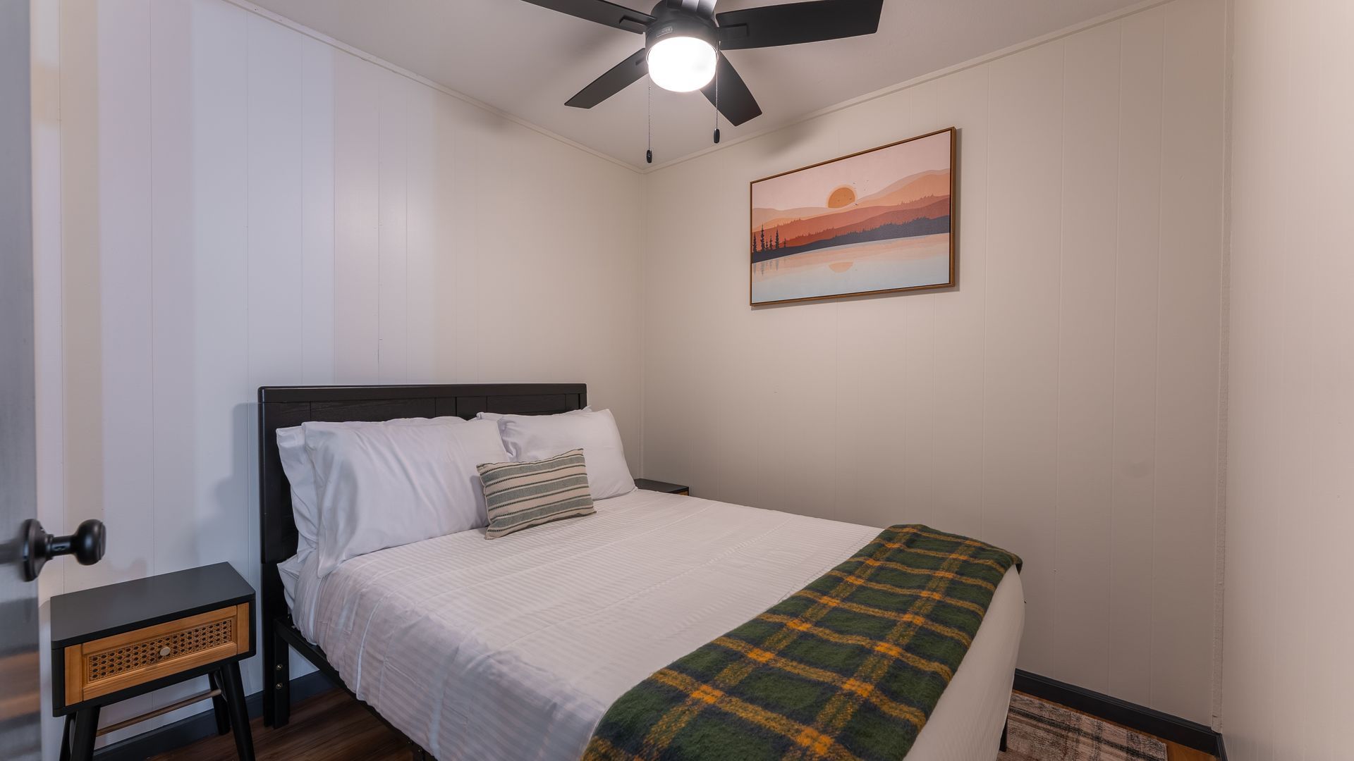 A bedroom with a bed , nightstand , and ceiling fan.