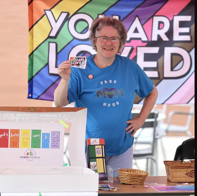 A woman standing in front of a sign that says you are loved