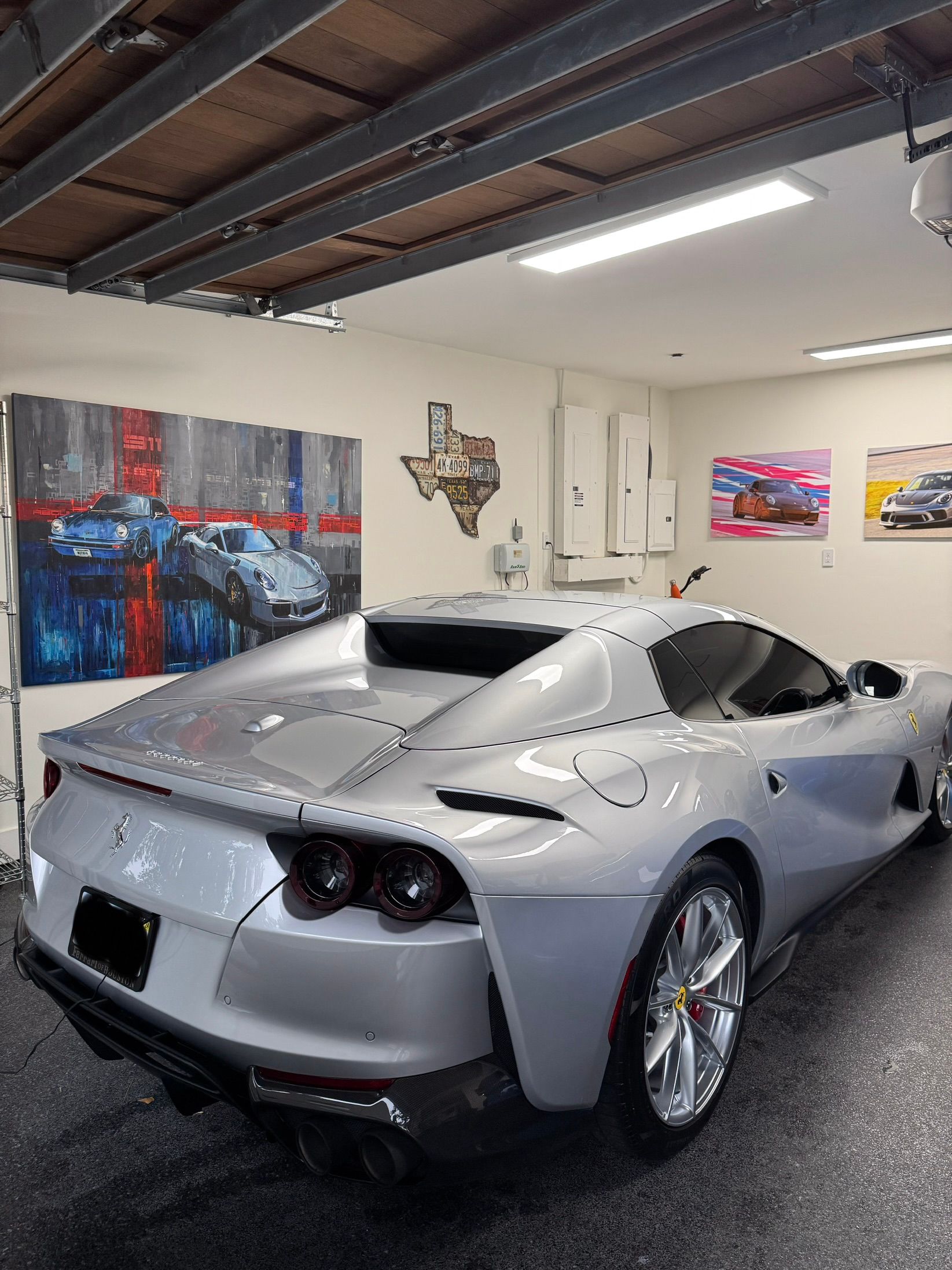 A white Porsche sports car covered in thick soap suds is parked on a wet surface outside a building.