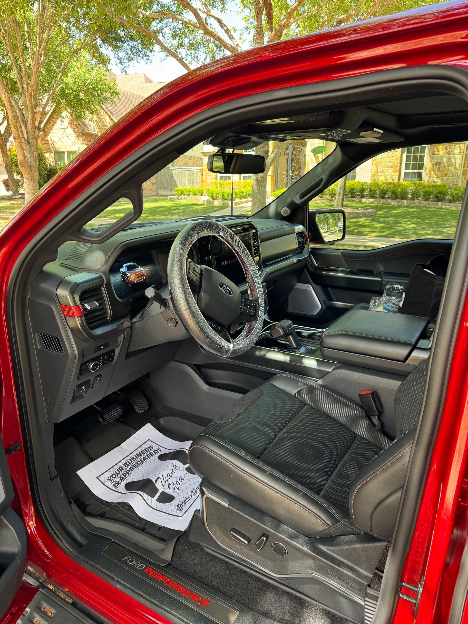 A gloved hand uses a brush and cleaning foam to scrub the center console and gear shifter of a car interior.